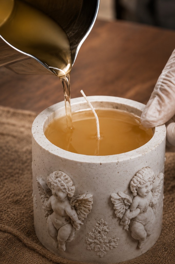 The Pour — warm wax filling an angel-relief candle vessel by Maelora