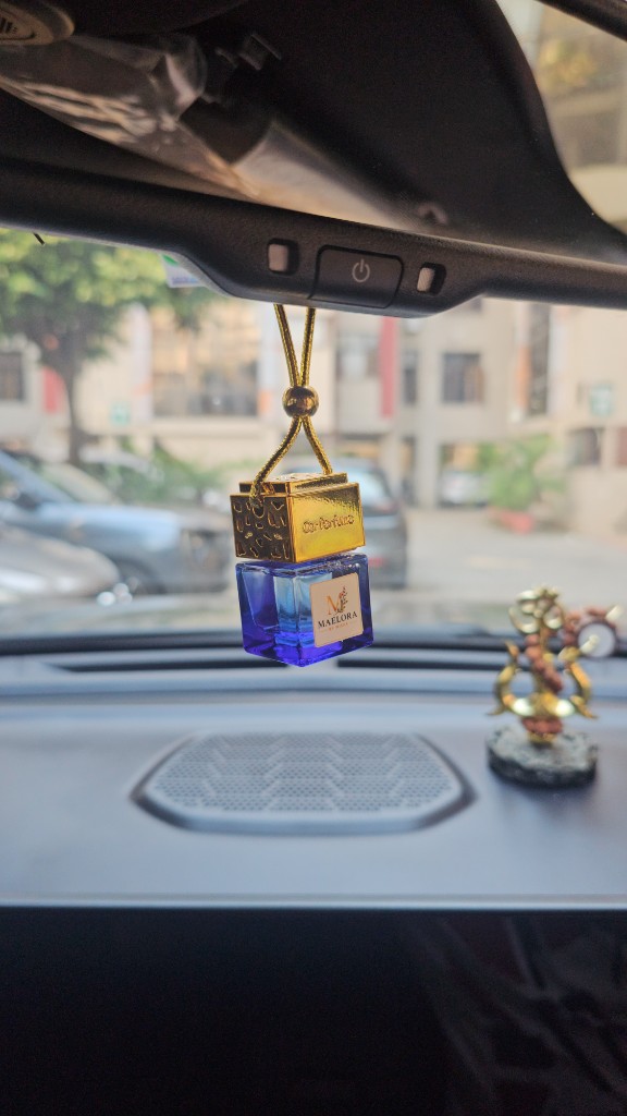 Maelora blue glass hanging car fragrance with gold cap on a rear-view mirror