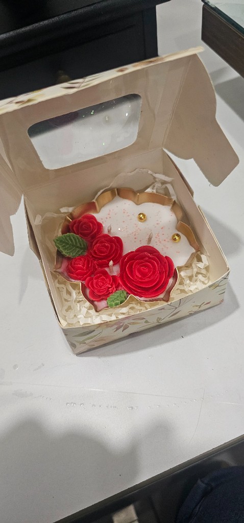 Small Urli Candle by Maelora in an open floral gift box with red wax roses and gold accents
